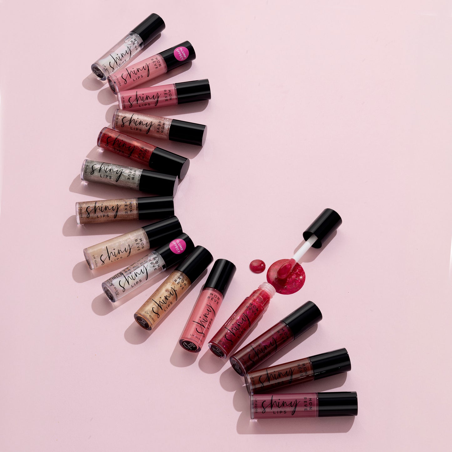 Mon Reve Shiny Lips læbegloss i mange farver med applikator på lyserød baggrund