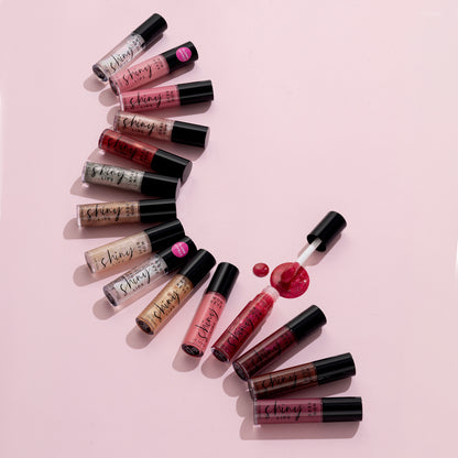 Mon Reve Shiny Lips læbegloss i mange farver med applikator på lyserød baggrund